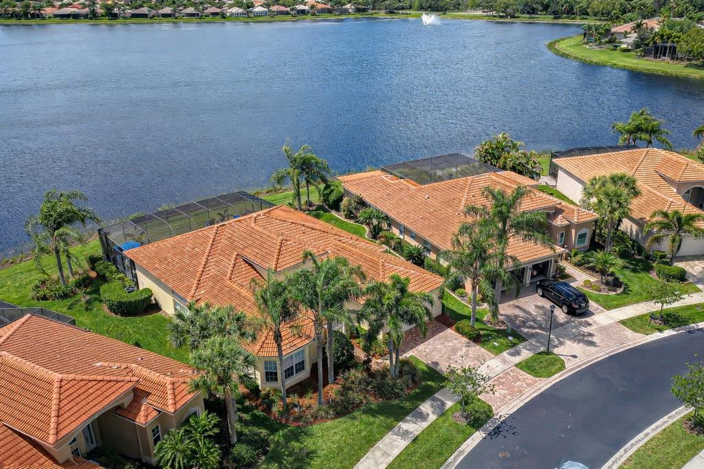 An aerial view shows several houses with orange tile roofs situated along a large lake — 5056 RUBY FLATS DRIVE, WIMAUMA, FL