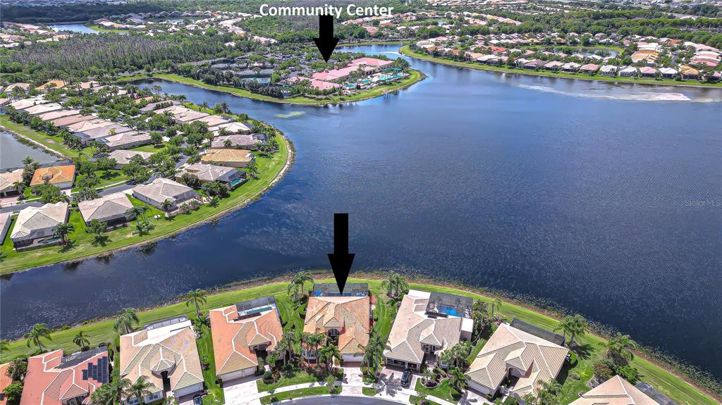 An aerial view shows a residential neighborhood with houses surrounding a large lake — 5056 RUBY FLATS DRIVE, WIMAUMA, FL