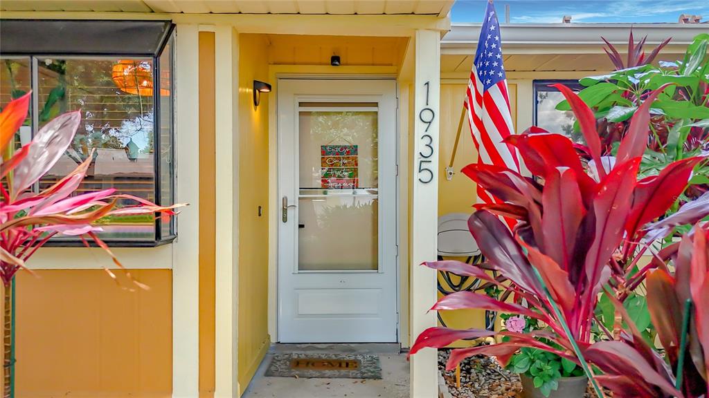 A front entrance with a white storm door, house numbers, and red-leafed plants — 1935 PEPPERMILL DRIVE UNIT C, CLEARWATER, FL