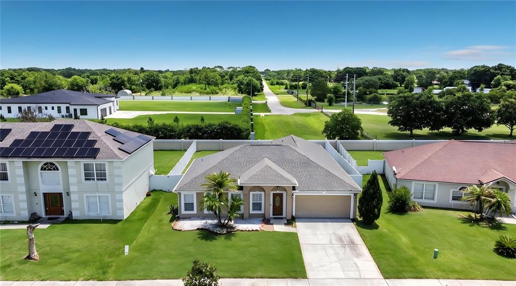 An aerial view shows a single-story suburban house with a tan exterior and gray roof — 3013 MANDOLIN DRIVE, KISSIMMEE, FL