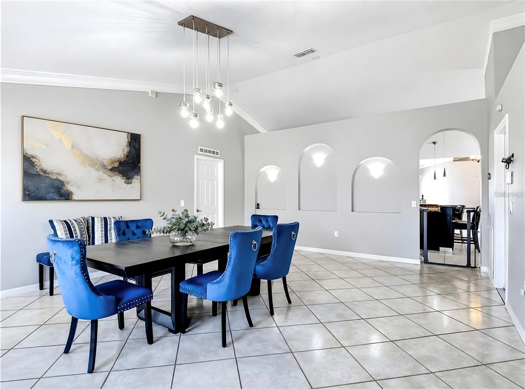 A dining room features a dark table, blue velvet chairs, and three arched wall niches — 3013 MANDOLIN DRIVE, KISSIMMEE, FL