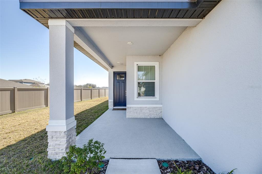 A covered front porch with a blue door, stone base pillar, and light-colored siding — 2707 VIRGINIA PINE DRIVE, BARTOW, FL