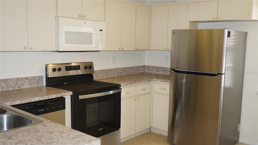 A kitchen with white cabinets, stainless steel appliances, and gray laminate countertops — 8907 SEELEY LANE, HUDSON, FL