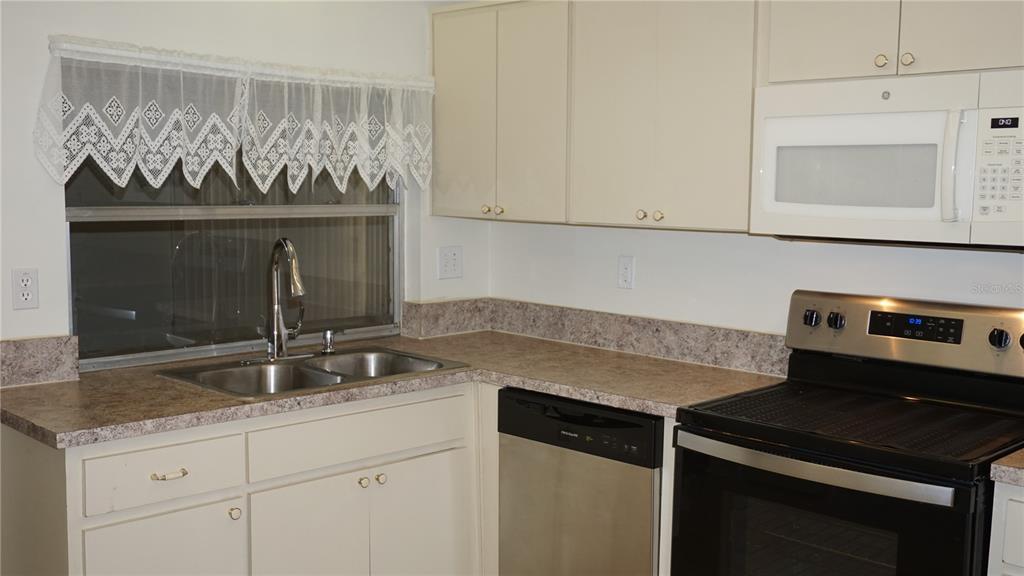 A kitchen features white cabinets, stainless steel appliances, a double sink, and laminate countertops — 8907 SEELEY LANE, HUDSON, FL