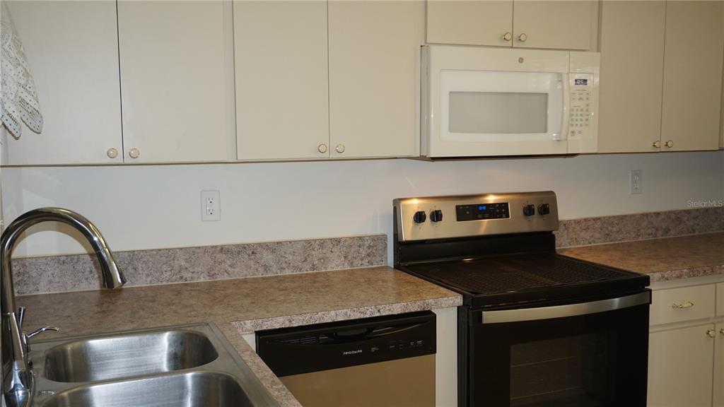 A kitchen features off-white cabinets, a stainless steel stove, a dishwasher, and laminate countertops — 8907 SEELEY LANE, HUDSON, FL