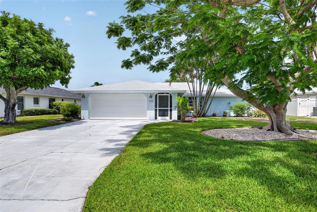 A light blue single-story house features a white garage door and a screened front entrance — 1226 PINE NEEDLE ROAD, VENICE, FL