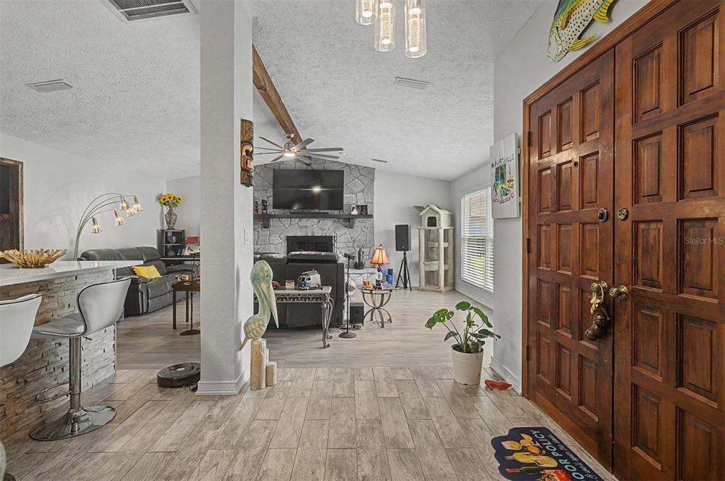 A view from an entryway into a living room with a stone fireplace and flooring — 3110 SHADOW OAKS DRIVE, HOLIDAY, FL