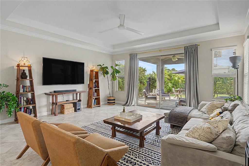 A living room features a large television, a coffee table, and a sliding glass door — 4447 TUBULAR RUN, LAND O LAKES, FL