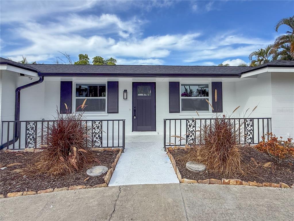 A white house exterior features a dark front door, black shutters, and a metal railing — 510 69TH STREET, HOLMES BEACH, FL