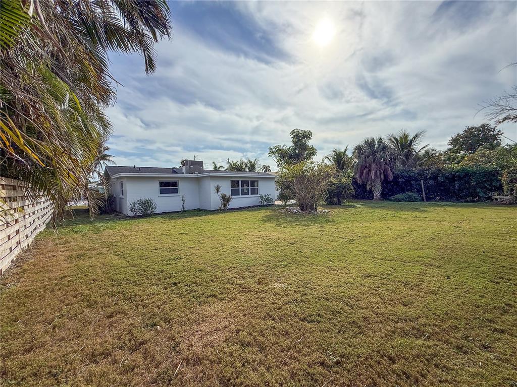 A white single-story house sits behind a large grassy yard under a sunny sky — 510 69TH STREET, HOLMES BEACH, FL