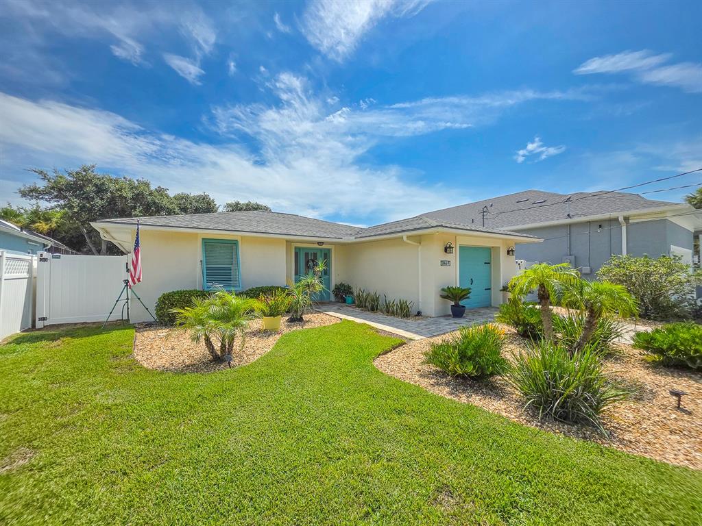 A single-story house with a light-colored exterior, a blue door, and a landscaped front yard — 2617 S DAYTONA AVENUE, FLAGLER BEACH, FL