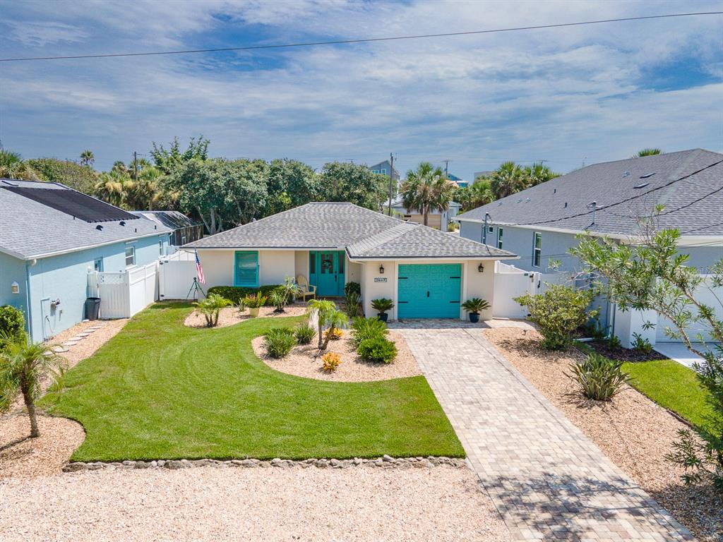 An exterior view of a single-story house with a turquoise door, garage, and landscaped yard — 2617 S DAYTONA AVENUE, FLAGLER BEACH, FL