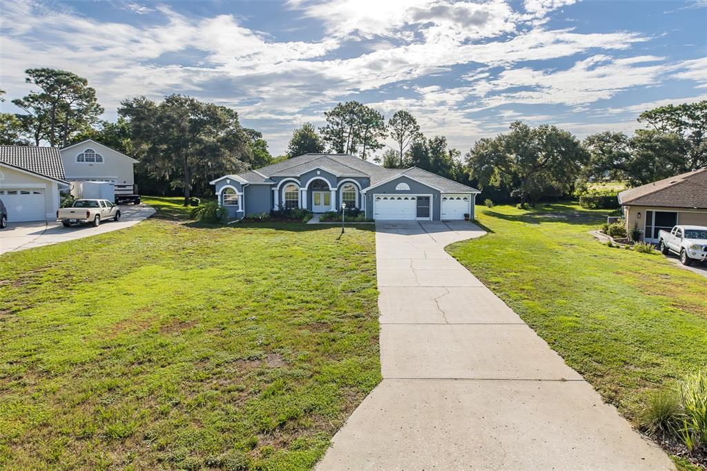 A blue single-story house with a three-car garage and a concrete driveway — 11382 DOXSEY HILL CIRCLE, SPRING HILL, FL