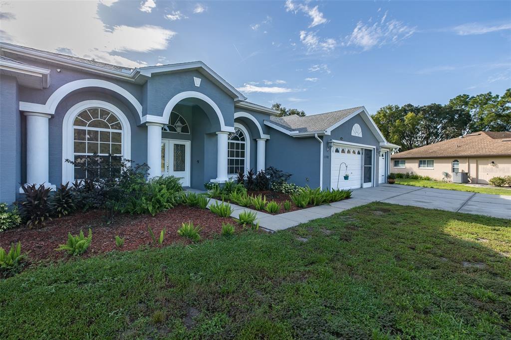 A blue single-story house with a white arched entryway and a two-car garage — 11382 DOXSEY HILL CIRCLE, SPRING HILL, FL