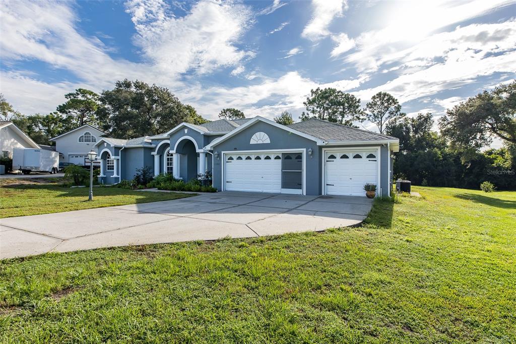 A blue single-story house with a white arched entryway and a two-car garage — 11382 DOXSEY HILL CIRCLE, SPRING HILL, FL
