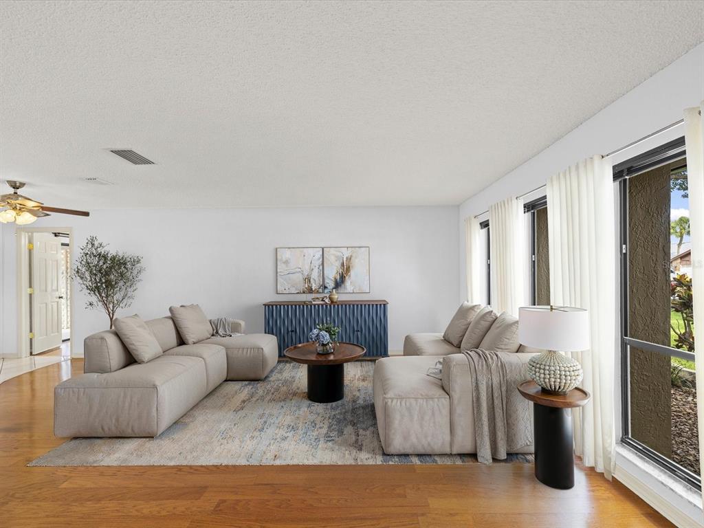 A living room features a sectional sofa, a round coffee table, and a blue sideboard — 10843 HARBORSIDE DRIVE, LARGO, FL