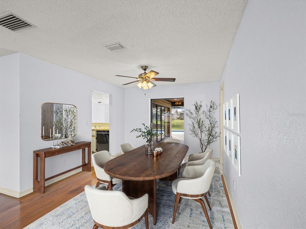 A dining room features a wooden oval table, six upholstered chairs, and a ceiling fan — 10843 HARBORSIDE DRIVE, LARGO, FL