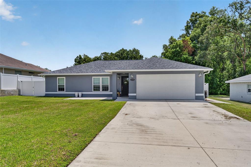 A gray single-story house with a white garage door and a concrete driveway — 8280 SE 161ST PLACE, SUMMERFIELD, FL