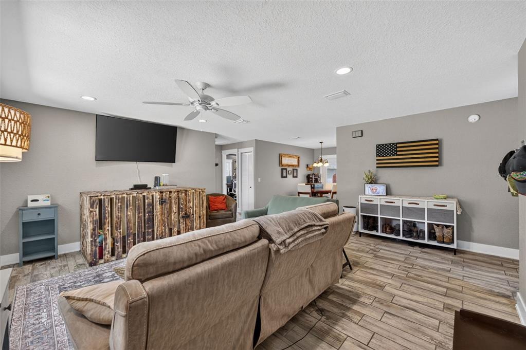A living room features a wooden media console, a beige sofa, and a wall-mounted flag — 8280 SE 161ST PLACE, SUMMERFIELD, FL