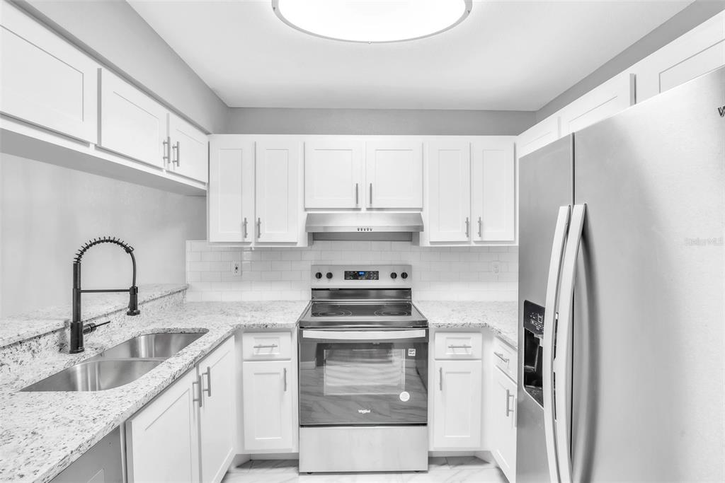 A kitchen features white cabinets, granite countertops, stainless steel appliances, and a subway tile backsplash — 3281 BENEVA ROAD UNIT 202, SARASOTA, FL