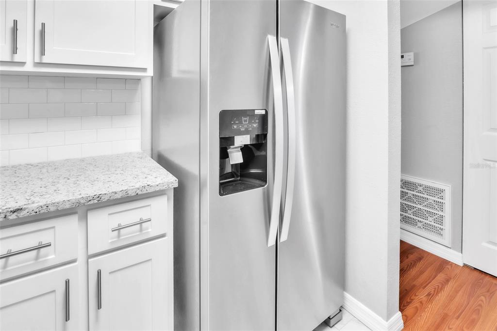 A stainless steel refrigerator stands next to white cabinets and a granite countertop — 3281 BENEVA ROAD UNIT 202, SARASOTA, FL