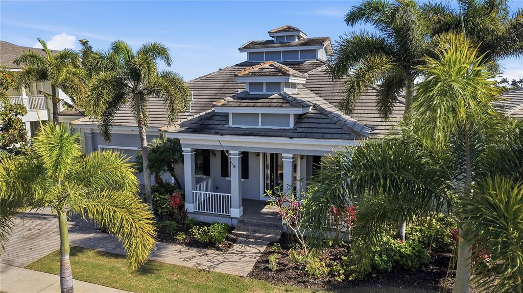 An exterior view of a single-story house with a tiered roof and palm trees — 510 MIRABAY BOULEVARD, APOLLO BEACH, FL