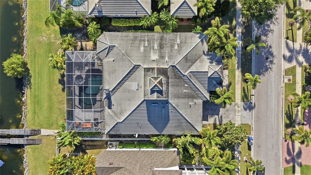 An aerial view shows a house with a tiled roof, pool cage, and waterfront backyard — 510 MIRABAY BOULEVARD, APOLLO BEACH, FL
