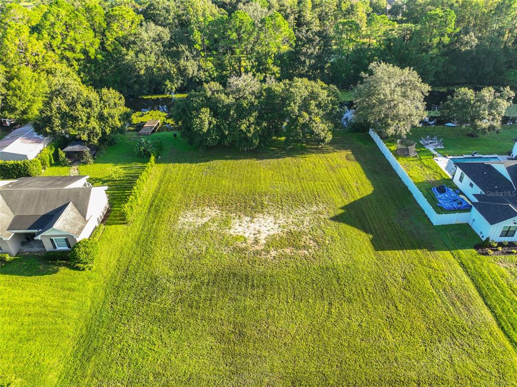 An aerial view shows a grassy vacant lot situated between two houses near a wooded waterway — 0 PHILLIPS ROAD UNIT 2, ODESSA, FL