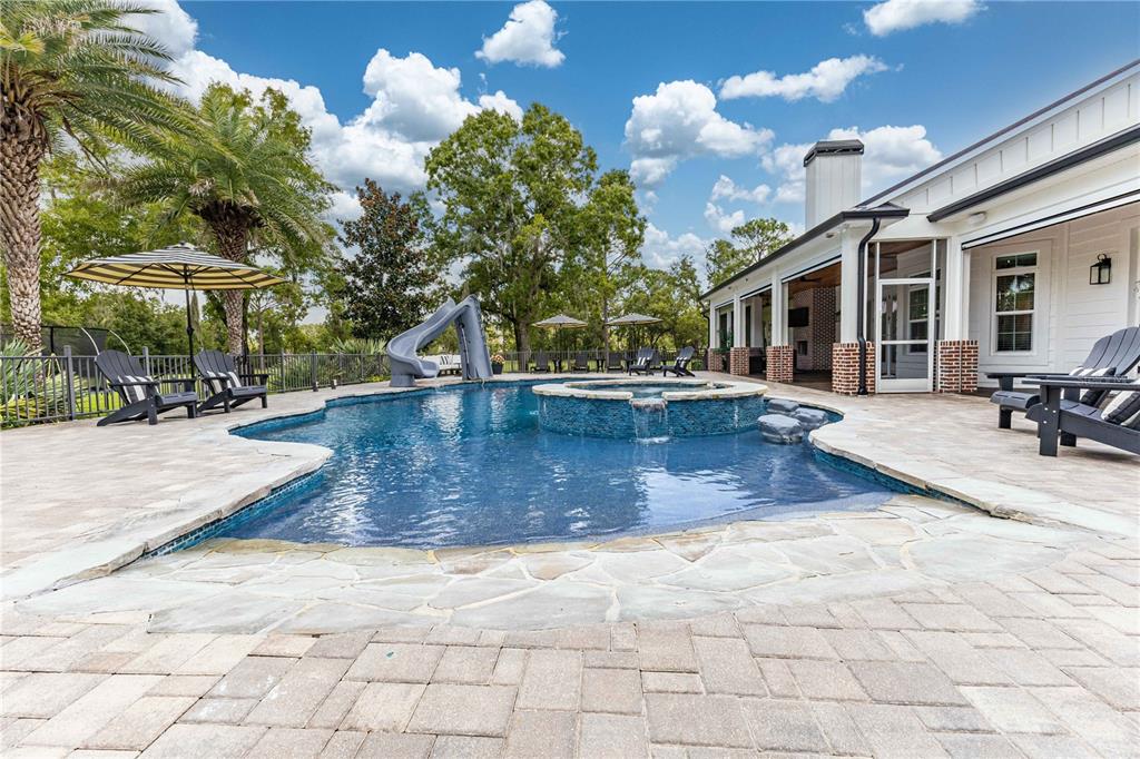 A backyard swimming pool with a slide, hot tub, and patio furniture next to a house — 2870 NW 87TH AVENUE, WILDWOOD, FL