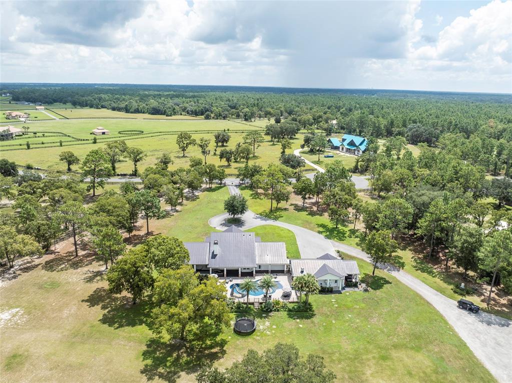 An aerial view shows a house with a metal roof, a pool, and a trampoline — 2870 NW 87TH AVENUE, WILDWOOD, FL
