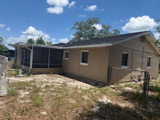 The exterior of a tan, single-story house features a screened-in porch and a chain-link fence — 2108 WOLF ROAD, ORLANDO, FL