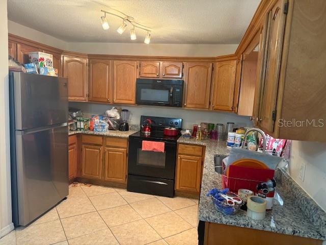 A kitchen features wood cabinets, stainless steel appliances, and granite-look countertops over tile flooring — 2108 WOLF ROAD, ORLANDO, FL
