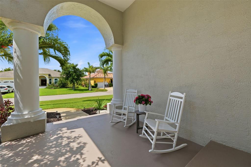 A covered front porch features two white rocking chairs and a small table — 631 DE SOTO DRIVE, TIERRA VERDE, FL
