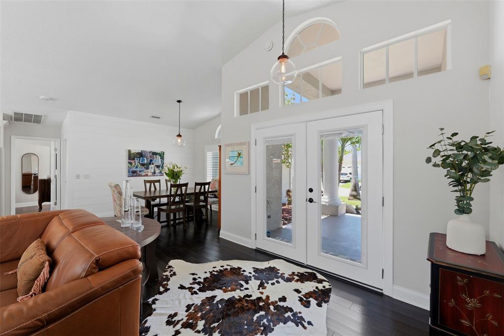 A living and dining area features dark wood floors, a cowhide rug, and double glass doors — 631 DE SOTO DRIVE, TIERRA VERDE, FL
