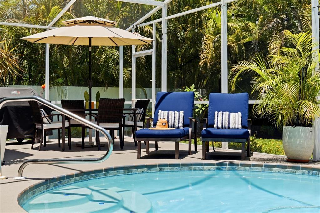 A pool deck features two blue lounge chairs, a dining set, and a patio umbrella — 631 DE SOTO DRIVE, TIERRA VERDE, FL