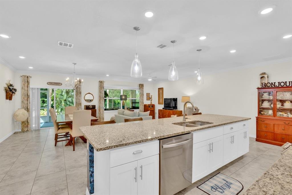 A kitchen island with granite countertops overlooks an open-concept dining area and living room — 801 GEORGE STREET, SEBASTIAN, FL