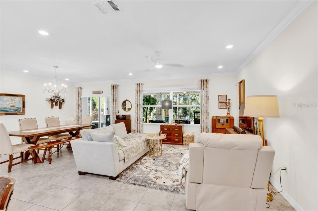 A bright open-concept living and dining area features tile flooring, neutral furniture, and large windows — 801 GEORGE STREET, SEBASTIAN, FL