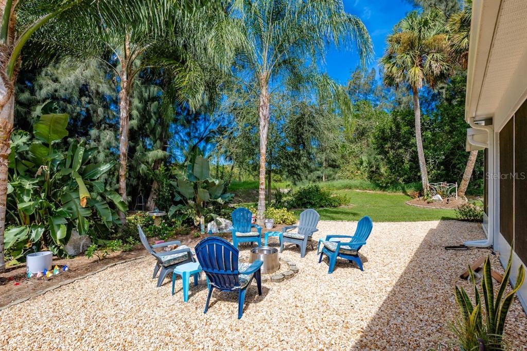 A backyard patio features a gravel surface, a fire pit, and several blue Adirondack chairs — 801 GEORGE STREET, SEBASTIAN, FL