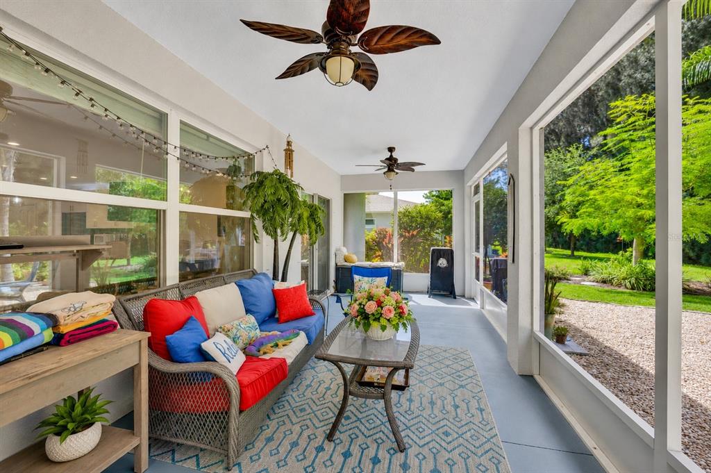 A screened-in patio features a wicker sofa with colorful cushions, a coffee table, and ceiling fans — 801 GEORGE STREET, SEBASTIAN, FL