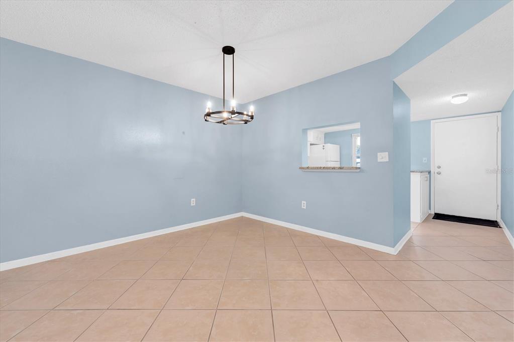 A dining area features light blue walls, tile flooring, and a modern black chandelier — 845 MAPLE COURT UNIT 103, DUNEDIN, FL
