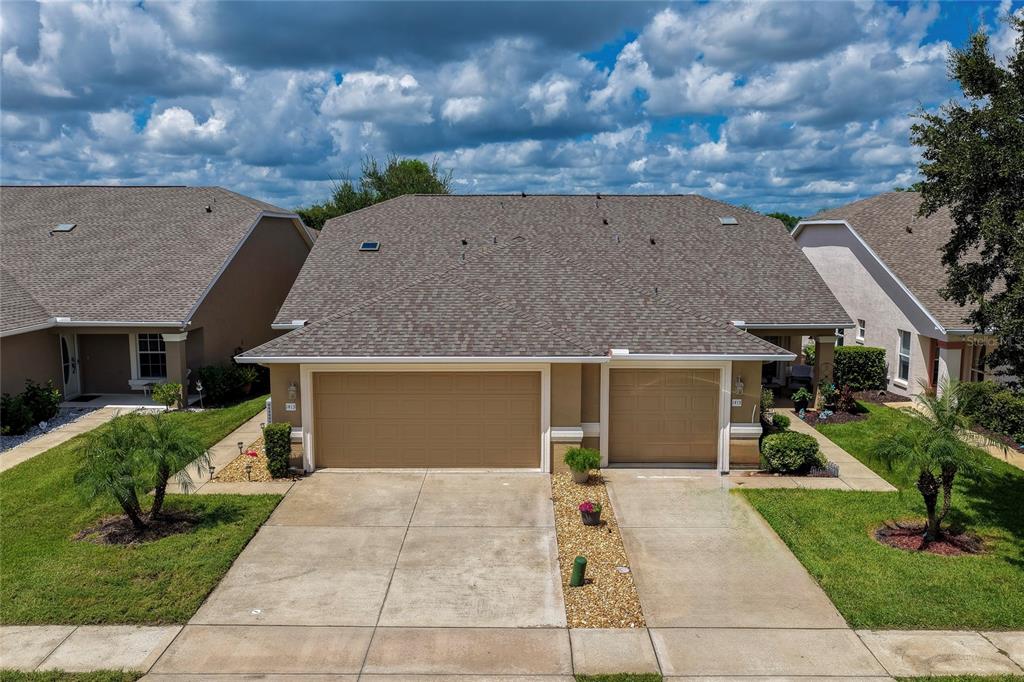 An exterior view of a duplex home with two garage doors and a shared driveway — 1413 COCONUT PALM CIRCLE, PORT ORANGE, FL