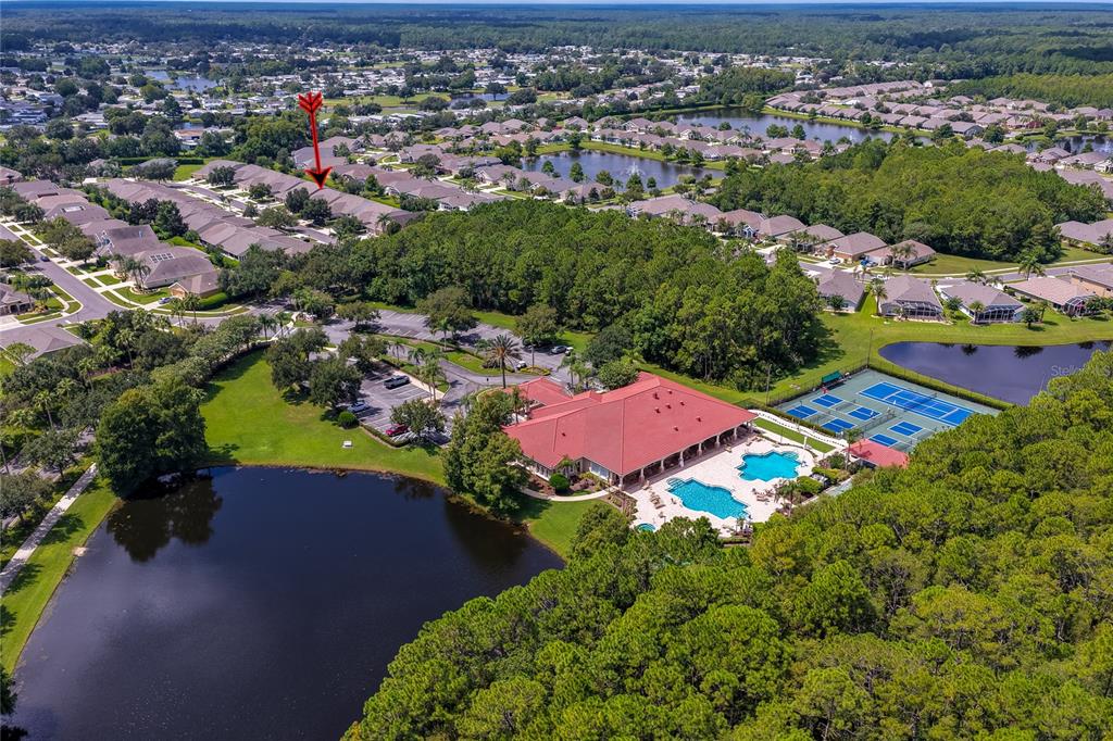An aerial view shows a community clubhouse with a pool, tennis courts, and surrounding ponds — 1413 COCONUT PALM CIRCLE, PORT ORANGE, FL