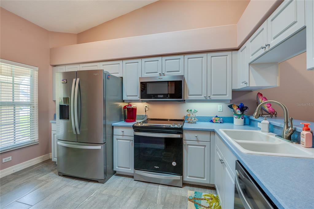 A kitchen features light gray cabinets, blue countertops, stainless steel appliances, and wood-look tile flooring — 1413 COCONUT PALM CIRCLE, PORT ORANGE, FL