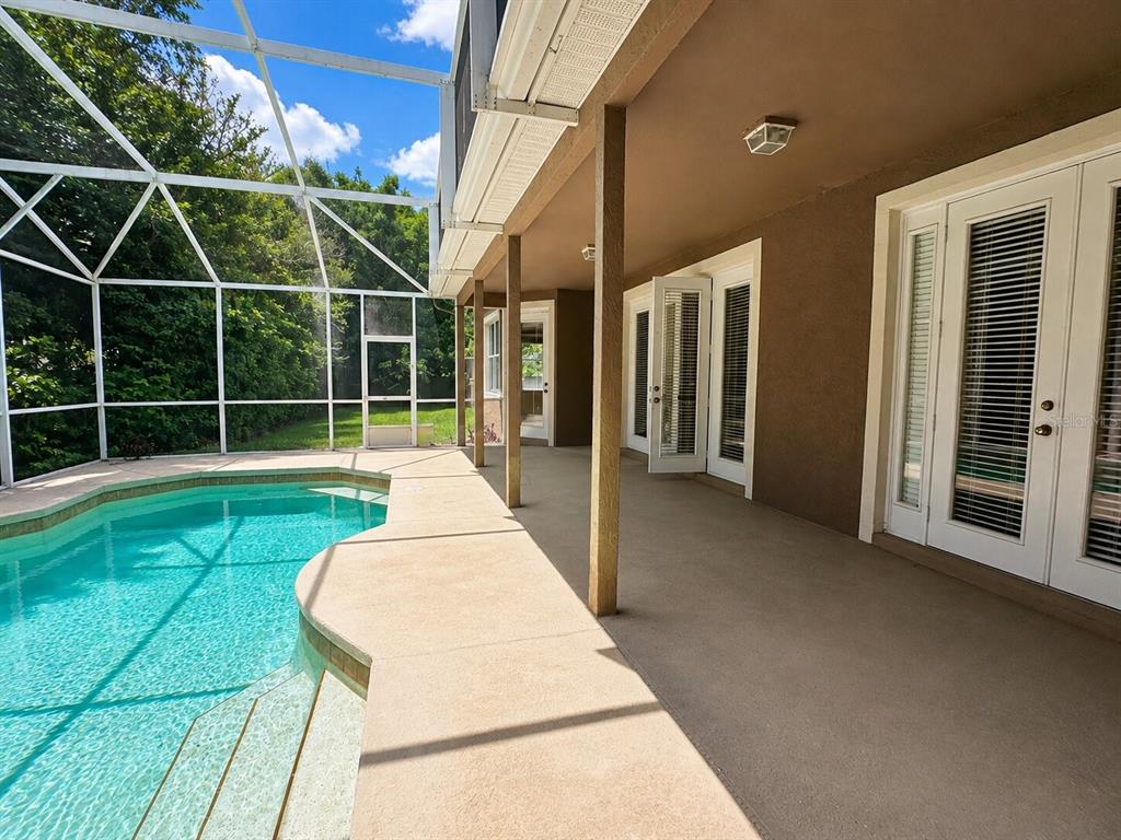 A covered patio with a swimming pool enclosed by a screen cage — 8650 TARA OAKS COURT, ORLANDO, FL