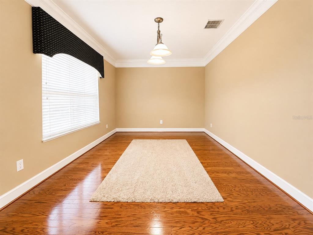 A dining room with hardwood floors, a beige area rug, and a window with a valance — 8650 TARA OAKS COURT, ORLANDO, FL