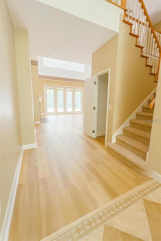 An entryway with light wood flooring leads to a living area with a staircase nearby — 8650 TARA OAKS COURT, ORLANDO, FL