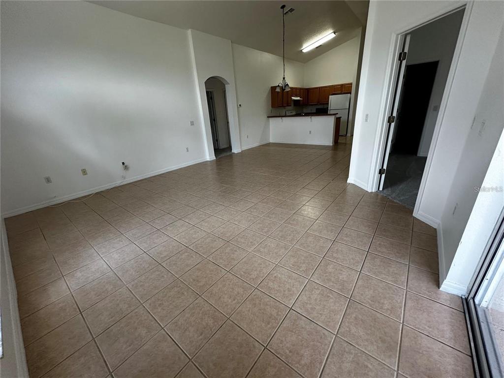 An open-concept living area features beige tile flooring, white walls, and an adjacent kitchen — 4795 CUMBRIAN LAKES DRIVE, KISSIMMEE, FL