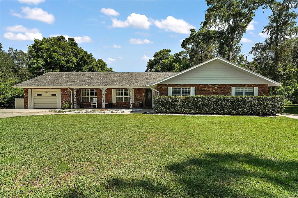 A single-story brick house with a garage, a front porch, and a large grassy lawn — 705 SUMMIT COURT, MOUNT DORA, FL