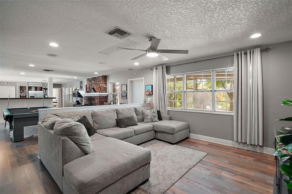 A living room features a large gray sectional sofa, a pool table, and a brick fireplace — 705 SUMMIT COURT, MOUNT DORA, FL