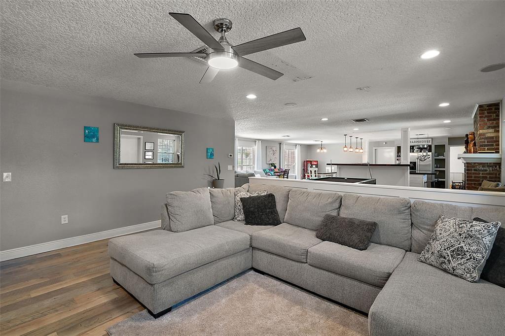 A gray sectional sofa sits in a living room with a ceiling fan and wood floors — 705 SUMMIT COURT, MOUNT DORA, FL